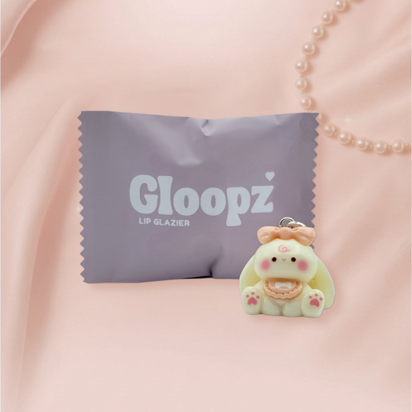 Gloopz lip glazier charm on a pink fabric background