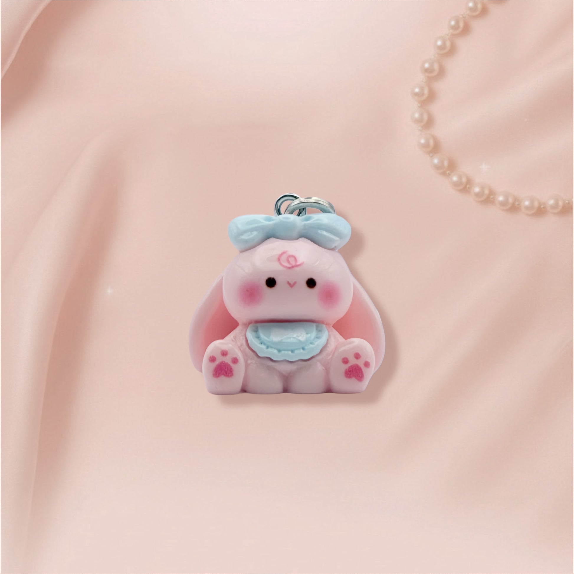 Pink bunny character charm with a blue bow on a pink background