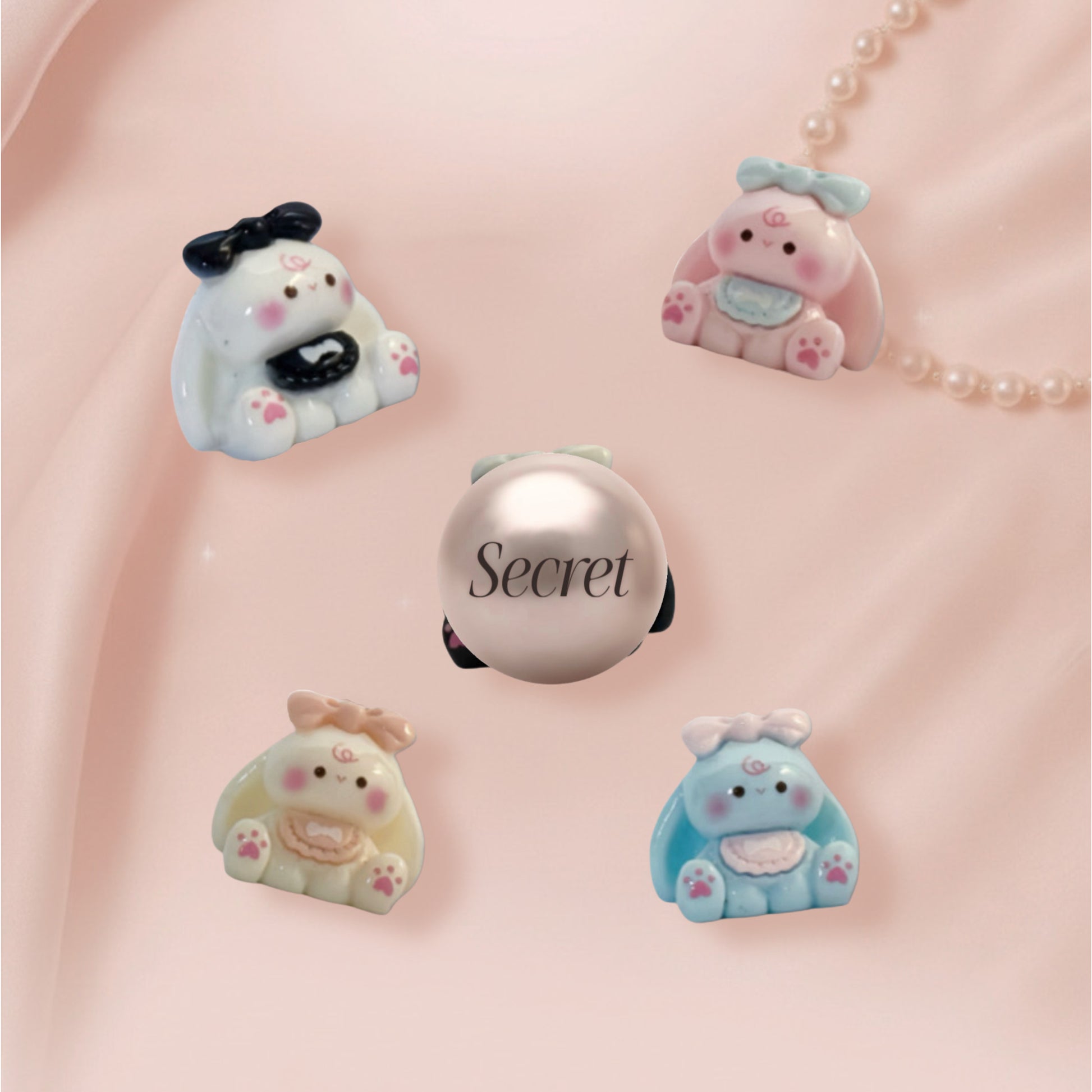 Set of cute bunny-shaped charms on a pink background