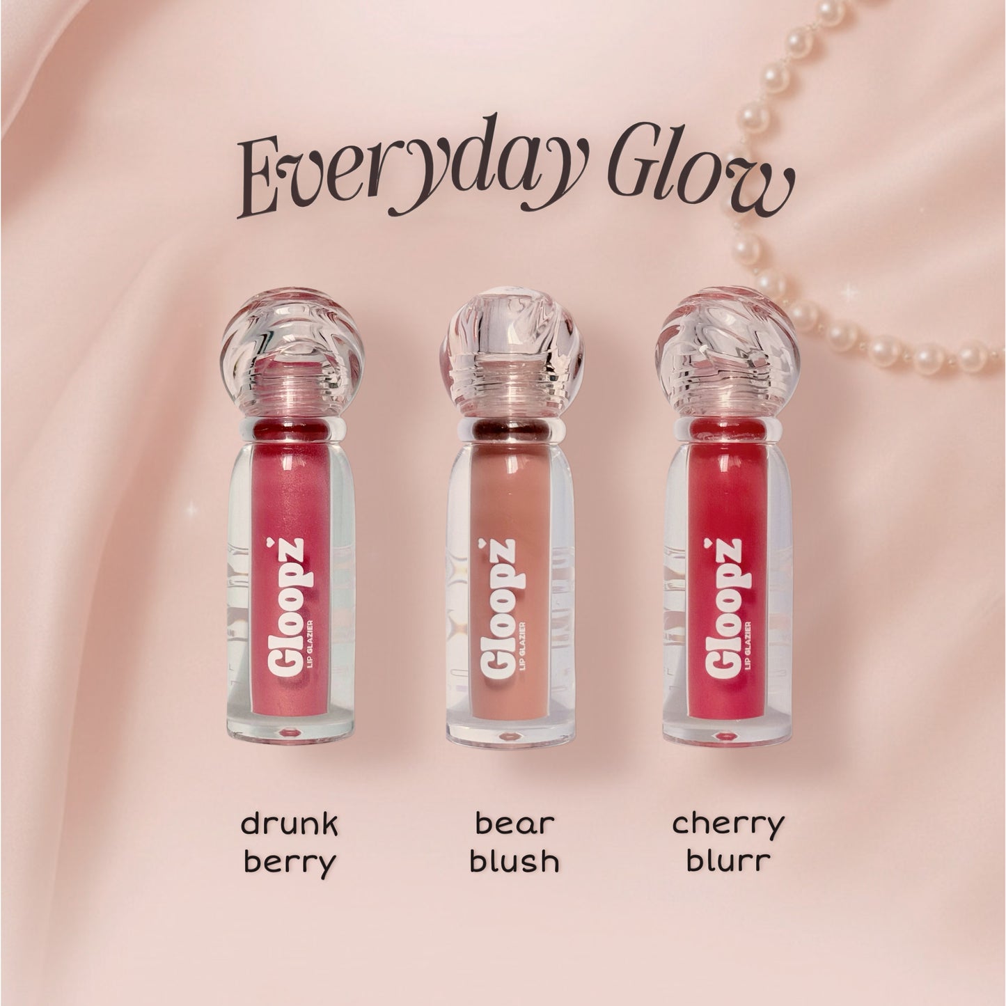 Three lip glosses with 'Gloopz' branding on a pink background, labeled 'drunk berry', 'bear blush', and 'cherry blurr'.