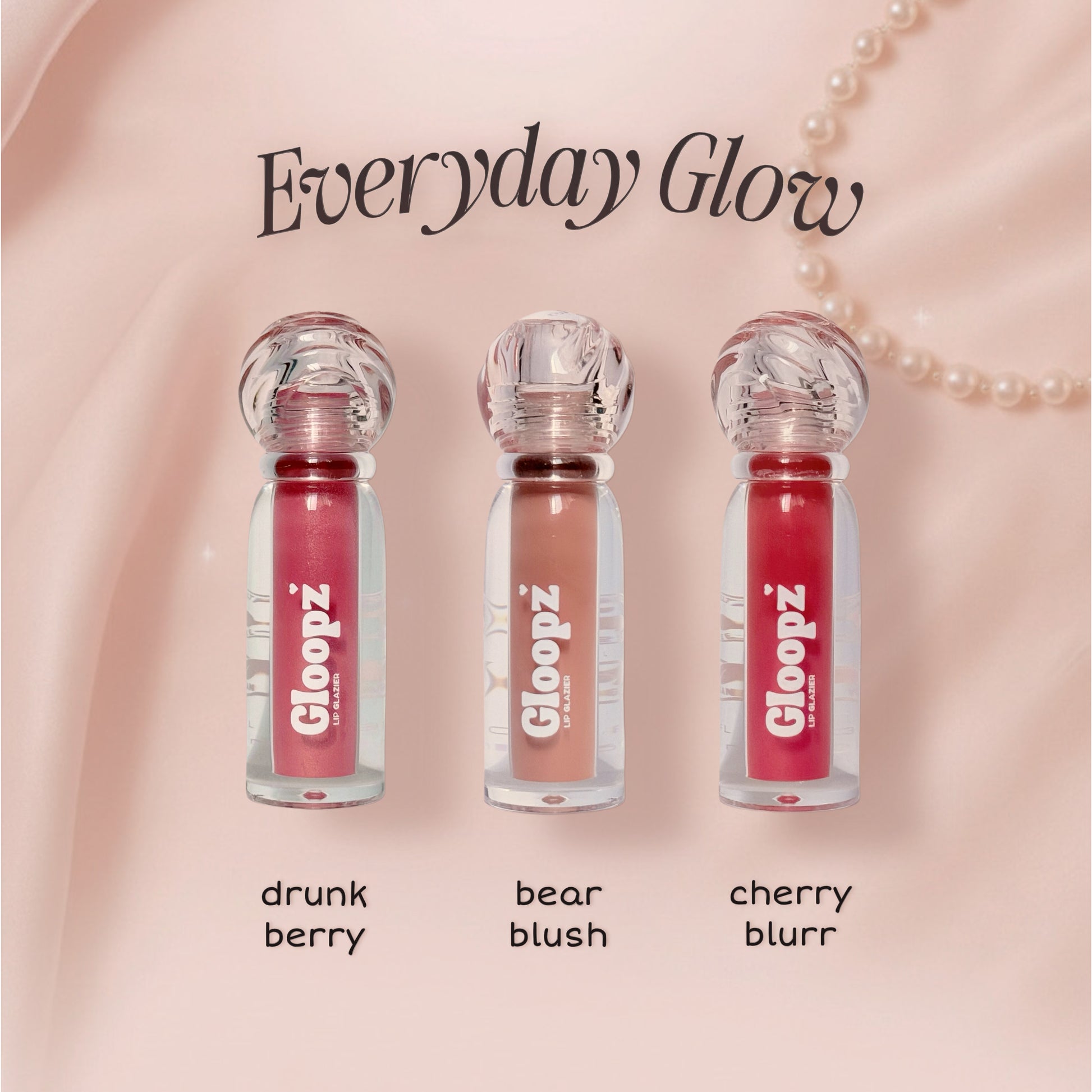 Three lip glosses with 'Gloopz' branding on a pink background, labeled 'drunk berry', 'bear blush', and 'cherry blurr'.