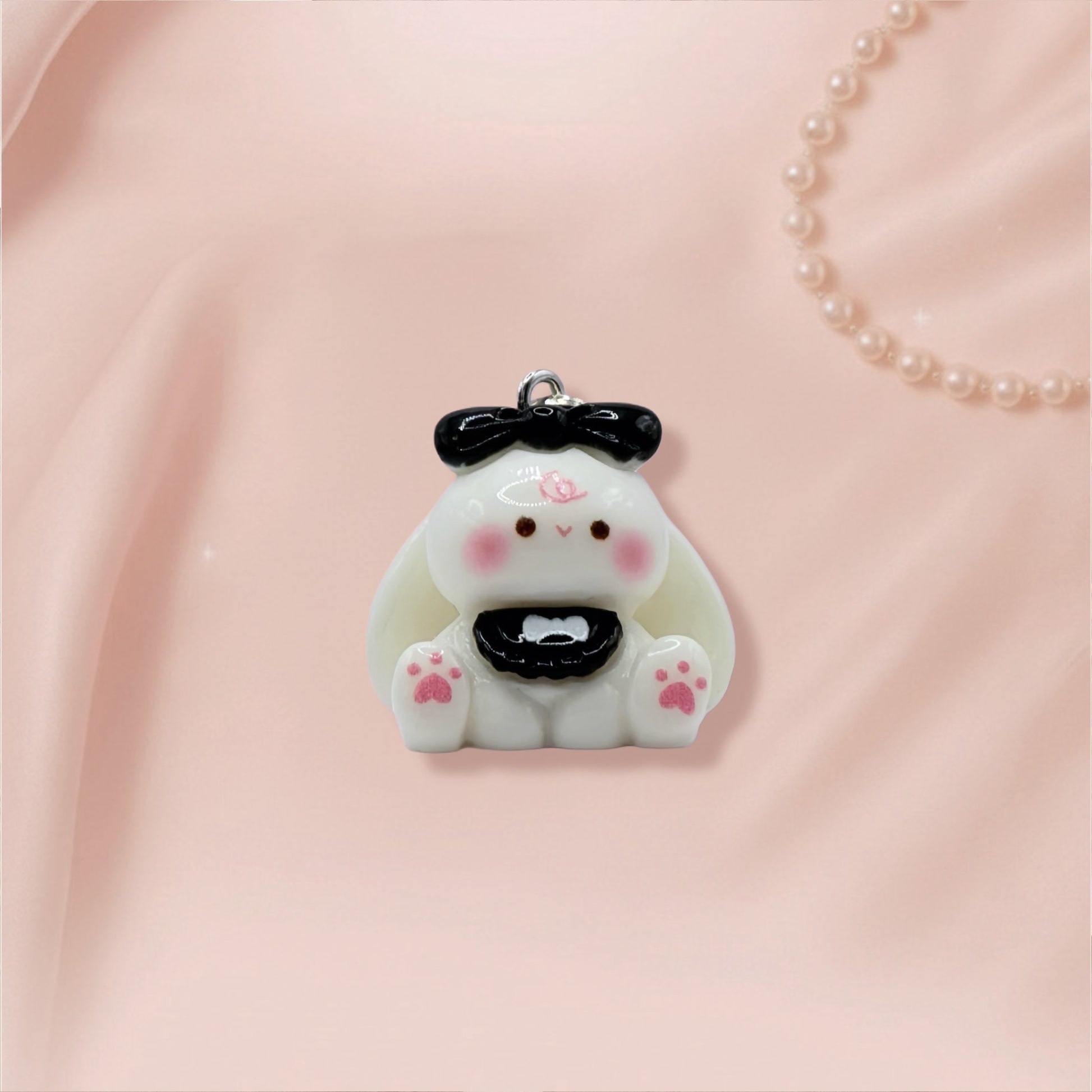 Cute bunny keychain with a black bow on a pink fabric background