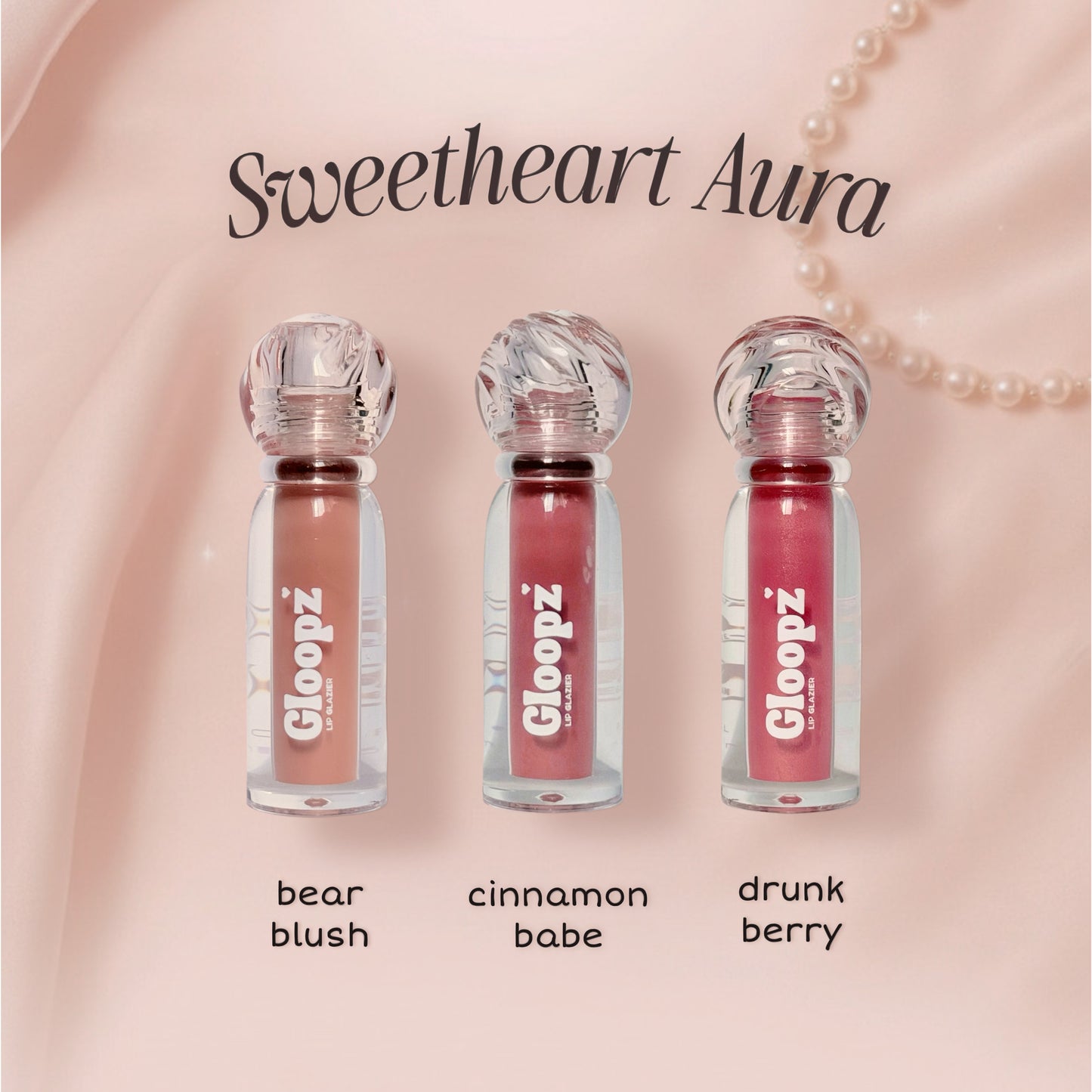Three lip glosses from Gloopz with names 'bear blush', 'cinnamon babe', and 'drunk berry' on a pink background.