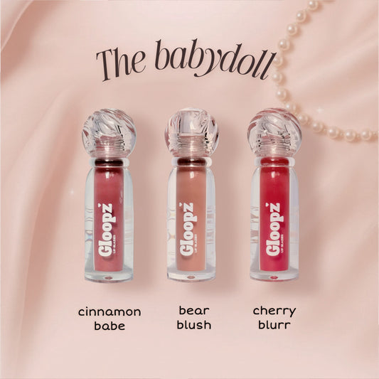 Three lip glosses from Gloopz on a pink background with 'The babydoll' text.